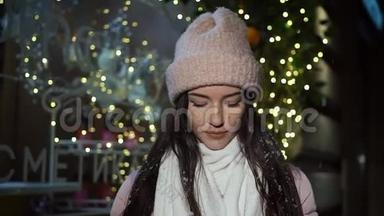 美丽迷人的女孩站在一家装饰着<strong>圣诞</strong>灯的<strong>橱窗</strong>商店旁边，看着相机。 咖啡